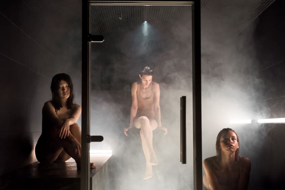 Women sitting in a steam sauna enjoying the benefits of lower temps and high humidity levels.